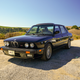 A black BMW M5 parked on gravel.